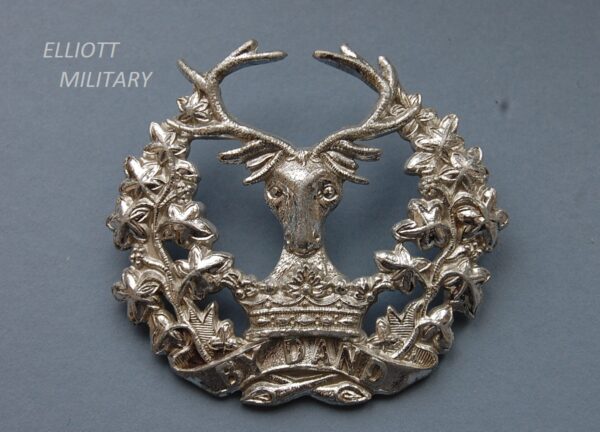 badge with stags head above a crown and scroll within a wreath
