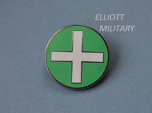 circular badge in green with white cross in centre