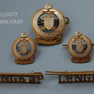5 badges, three with shield depicting 3 cannons with crossed kris knives and anchor within a titled scroll below a crescent moon and star. The other 2 badges reading LENGKAP