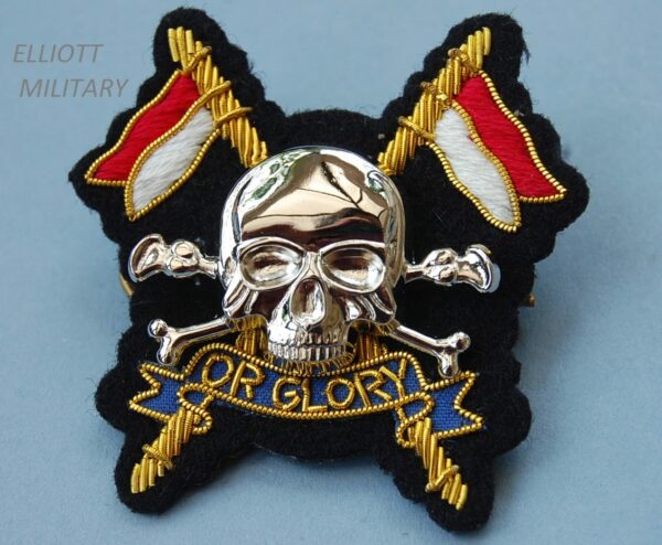 badge with metal scull and crossed bones mounted on cloth backing badge with crossed lances and scroll reading Or Glory