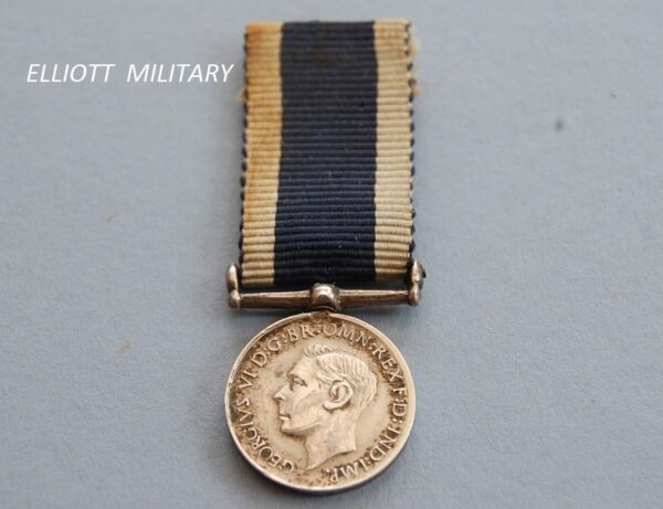 miniature medal with the head of King George the sixth on a blue ribbon with white edges