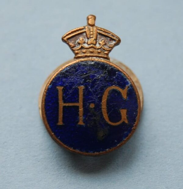 badge with crown above the letters H.G on a blue enamel field