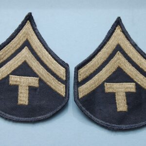 pair of cloth badges with two inverted chevrons above a capital letter T